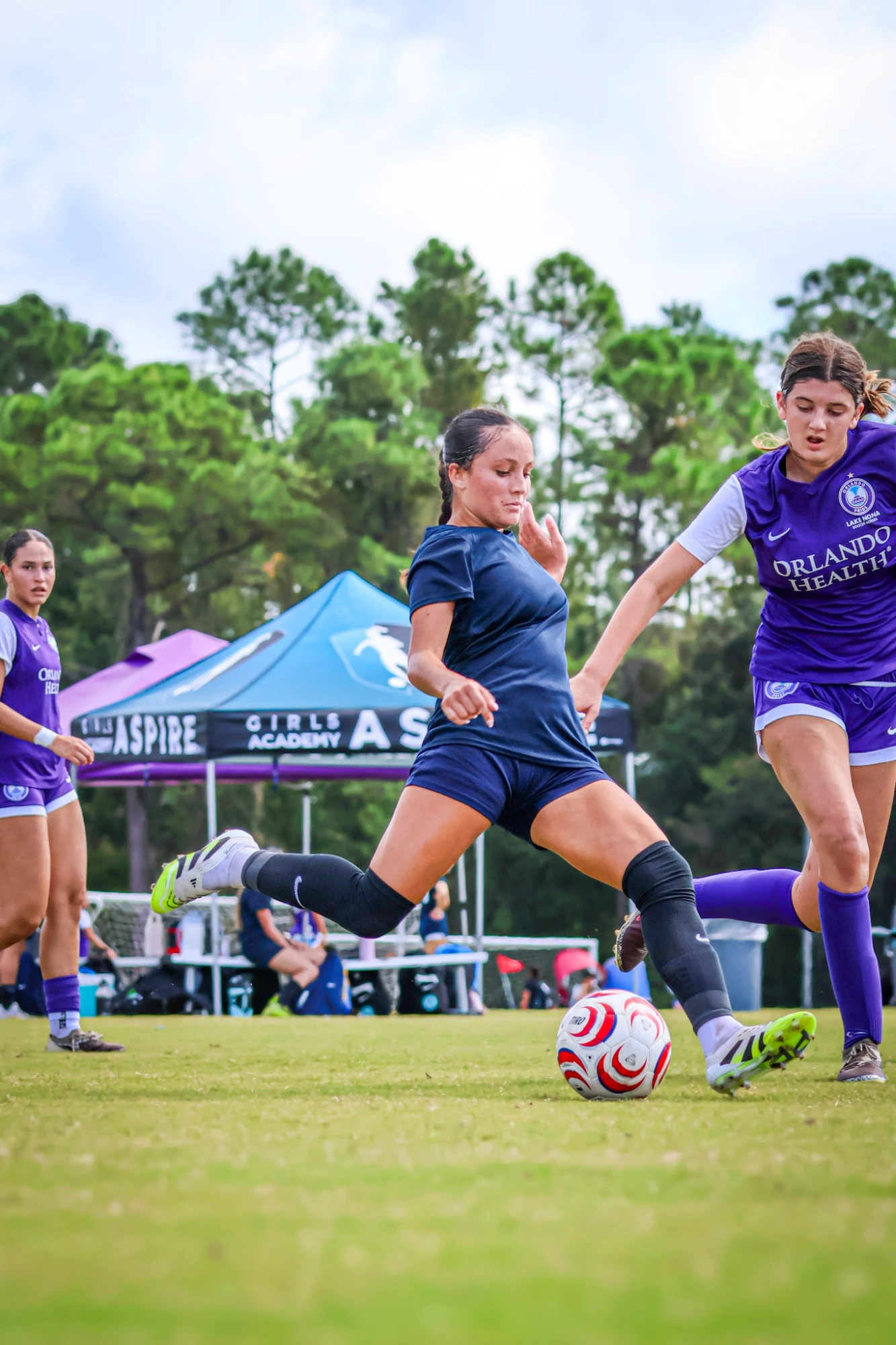 Soccer player striking the ball past a defender